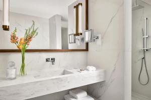 Un baño con un lavabo y un jarrón de flores. en Tivoli Avenida Liberdade Lisboa – A Leading Hotel of the World, en Lisboa
