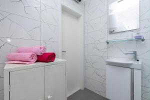 une salle de bain blanche avec des serviettes roses sur les meubles dans l'établissement Apartments Antonio, à Duće 30 autres photos