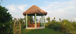 a gazebo with a thatch roof and a playground at Nili Farm House in Shānti Niketan