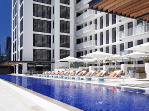 Una piscina de hotel con tumbonas y sombrillas. en The Johnson Brisbane - Art Series, en Brisbane