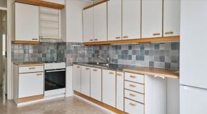 a kitchen with white cabinets and a sink at Kotimaailma - kolmio Kotkan kupeessa in Kotka