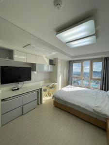 a bedroom with a bed and a desk with a television at 트루엘 레지던스 in Seogwipo