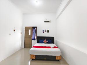 a bedroom with a bed in a white room at YUTAKA INN Bypass Mojokerto in Mojokerto