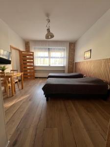 a bedroom with two beds and a table and a window at Louis Apartaments in Skorka