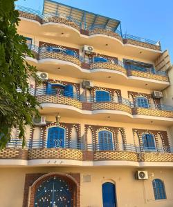 un edificio de apartamentos con ventanas azules y balcón en Gîte Hôtel Ramla Louxor 2, en Luxor