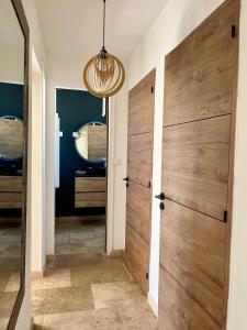 a hallway with a wooden door and a mirror at Cocon jungle bohème 12 min de la mer in Martigues