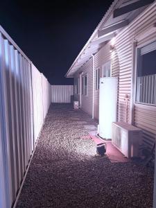 Eine Gasse mit einem Kühlschrank neben einem Zaun bei Nacht in der Unterkunft Newman Short Term Accommodation Rooms in Newman