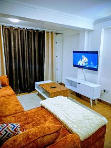 a living room with a couch and a flat screen tv at Cosmic home in Thika