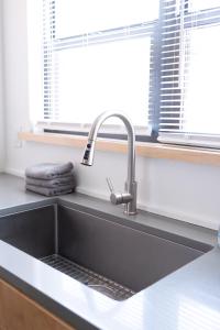 eine Küchenspüle mit einem Wasserhahn neben einem Fenster in der Unterkunft Elegant 2BR Escape in Manhattan with WiFi & Parking in Manhattan + 39 Fotos