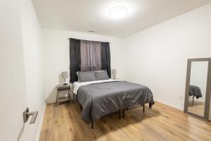 ein weißes Schlafzimmer mit einem Bett und einem Spiegel in der Unterkunft Elegant 2BR Escape in Manhattan with WiFi & Parking in Manhattan