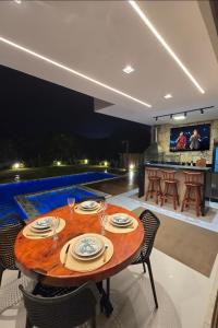 ein Esszimmer mit einem Tisch, Stühlen und einem Pool in der Unterkunft Maravilhosa Casa 5 Quartos-Reserva de Sauípe in Costa do Sauipe