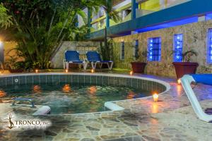 Hotel El Tronco Inc في بوكا شيكا: مسبح في فندق والكراسي الزرقاء والاضائه