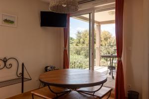 ein Esszimmer mit einem Tisch und einem Balkon in der Unterkunft Hotel Restaurant Le Gardon - Pont du Gard in Collias