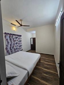 Un dormitorio con una cama y un ventilador de techo. en Mount Wave Holiday Pool Villa, en Wayanad