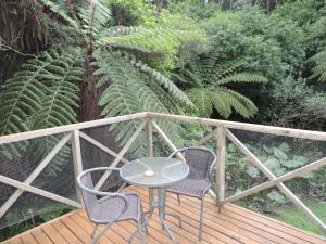 a table and two chairs on a deck with plants at Waiheke Island Punga Lodge in Oneroa