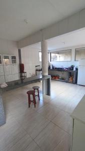 eine große Küche mit einem Tisch und einem Hocker darin in der Unterkunft casa de praia a 5 minutos da praia central in Marataizes