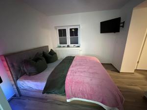a bedroom with a bed with a pink blanket at Karolinas Deluxe Appartement-Bungalow in Dranske