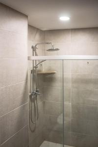 een douche met een glazen deur en een wastafel bij Crystal Loft Bakuriani Apartment in Bakuriani