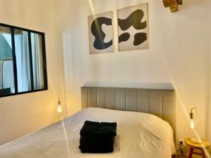 a bedroom with a bed with a black bag on it at Logement neuf tout équipé, climatisé, terrasse au calme, VELOS, barbecue, proche du bourg et des plages océanes, wifi, linge et ménage compris in Mimizan