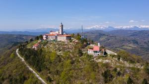 a building on top of a hill in the mountains at Guesthouse Rajski okusi Sveta Gora in Solkan