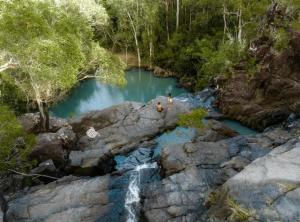 ein Becken mit blauem Wasser in einem Fluss mit einem Wasserfall in der Unterkunft Escape To Mango House in Airlie Beach