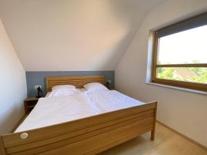 a bedroom with a bed with white sheets and a window at Haus 24 im Natur Ferienpark, Perfekt für Hundeliebhaber, Wanderfreunde und Naturliebhaber in Nieheim