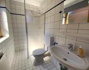 a white bathroom with a toilet and a sink at Haus 24 im Natur Ferienpark, Perfekt für Hundeliebhaber, Wanderfreunde und Naturliebhaber in Nieheim +14 photos