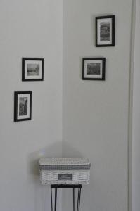 Eine weiße Wand mit drei gerahmten Bildern und einem Korb auf einem Tisch in der Unterkunft Die Ferienwohnung Chäserruggblick mit Charme in Unterwasser