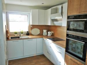 una cucina con mobili bianchi e una finestra di Ferienbungalow Fehmarnblick a Presen