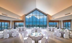 万荣万荣市阿玛里酒店的有白色桌椅和窗户的宴会厅