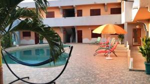 a pool with a swing and an umbrella next to a building at LA Rose Des Sables in Saly Portudal
