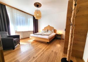 a bedroom with a bed and a chair in a room at Krautgasser Appartements in San Candido
