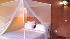 a canopy bed with white pillows in a room at LA Rose Des Sables in Saly Portudal +5 photos