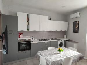 a kitchen with a table and white cabinets and a table and chairs at Al civico 14 in Foggia
