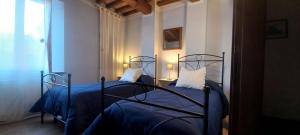 a bedroom with two beds with blue sheets at La Corte Antica in Pienza