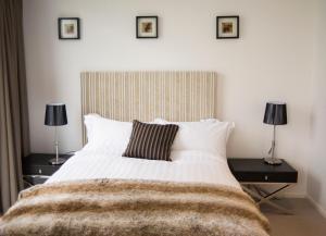 a bedroom with a large white bed with two lamps at KUI - Manhattan Apartments in Canberra