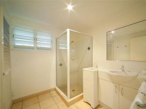 une salle de bain blanche avec lavabo et douche dans l'établissement Mango Eden Villa, à Airlie Beach