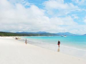 a group of people walking on a white beach at Mango Eden Villa in Airlie Beach