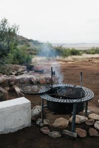 a fire pit with a grill in a field at Bergendam Eco Lodge in Venterstad