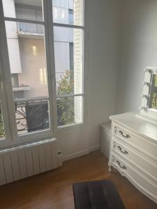 a white room with a dresser and two windows at Cute appartement in Boulogne-Billancourt