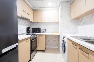 a small kitchen with white marble walls and cabinets at Azure Sands 2BR Escape with Priavte Beach and Pool in Al Marjan Island in Ras al Khaimah