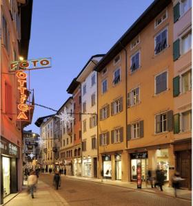 une rue de la ville avec des bâtiments et une enseigne au néon dans l'établissement Trento best home, à Trente