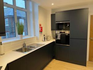 a kitchen with black cabinets and a sink and a window at The Old Town Hall - Flat 4 in Grove