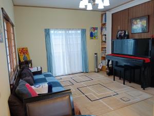a living room with a blue couch and a piano at 憩の家丸々貸し in Okazaki
