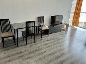 ein Esszimmer mit Tisch und Stühlen und einem Fernseher in der Unterkunft Atlantis Resort & 4 swimming pools & Spa & Апартамент in Burgas City