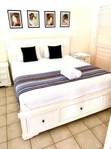 - un grand lit blanc dans une chambre avec des photos sur le mur dans l'établissement Coral Mango, à Airlie Beach