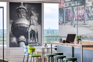 a bar with green and blue chairs in a room at ibis Berlin Messe in Berlin