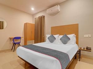 une chambre d'hôtel avec un lit et une chaise bleue dans l'établissement Townhouse White Ridge KPHB OPP JNTU, à Hyderabad 62 autres photos