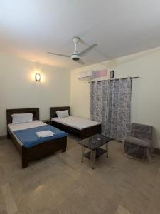 a room with two beds and a ceiling fan at Family Inn Guest House in Karachi