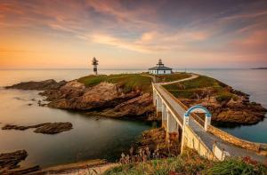 een pad dat naar een vuurtoren op een klif leidt bij Vaniria 3 Apartamentos Nuevos in Foz